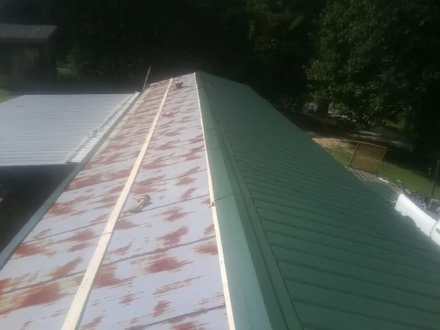 Old rusted panels beside newly installed green metal roofing — Wind Damage Roof Repair by Roofing Brothers in Gulf Hammock
