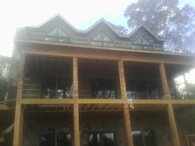 Dormers and porch framing on a large log home under construction — Roof Coating work by our crew in Gulf Hammock