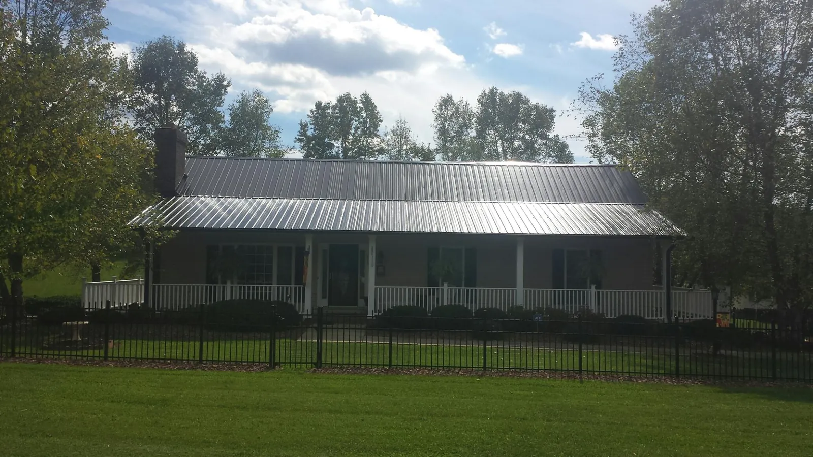 Gray metal roof on a brick ranch with a full width front porch — Gutter Guard Installation work by our crew in Gulf Hammock