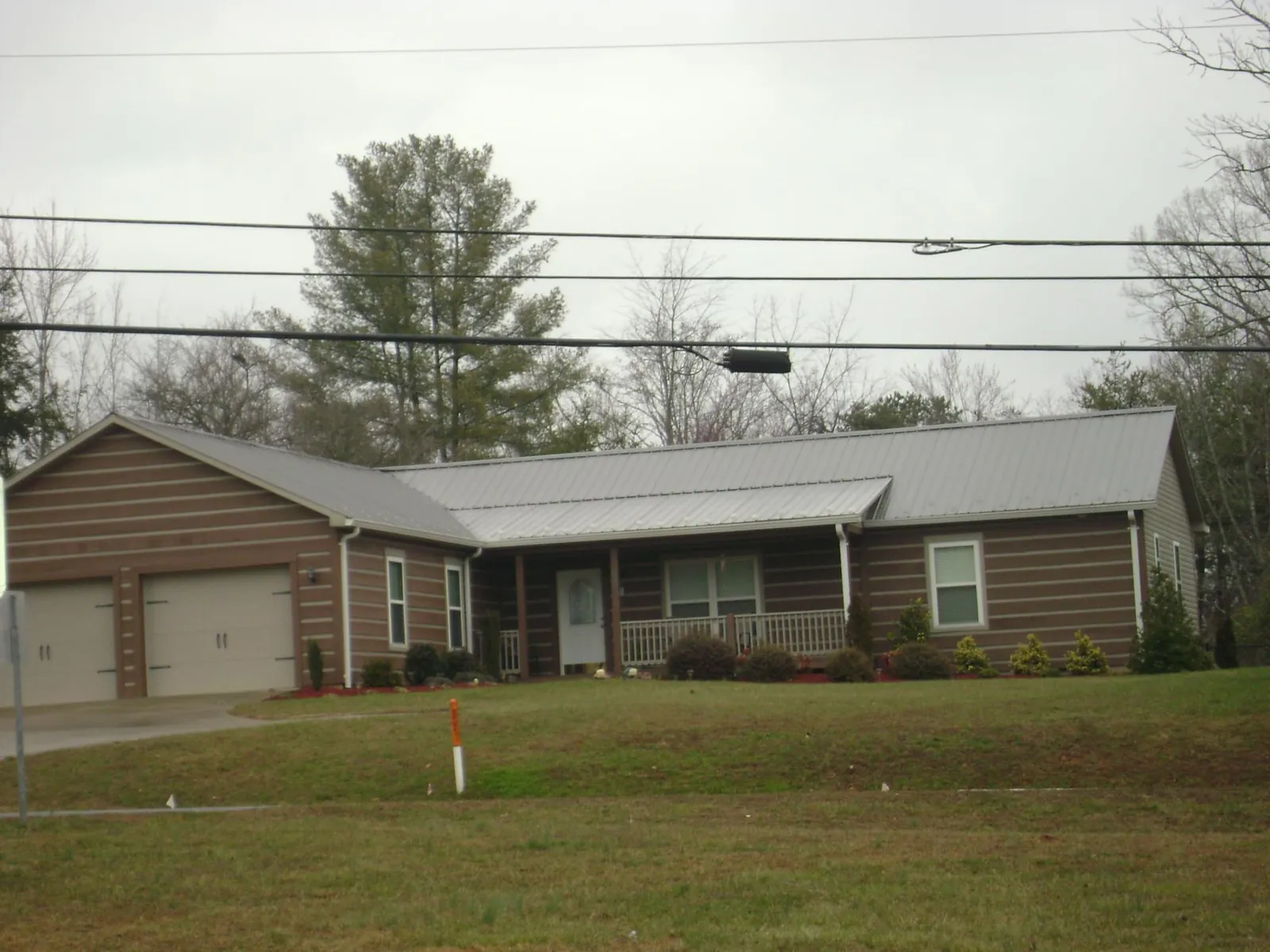 Gray metal roof on a log sided ranch home with a front porch in Gulf Hammock