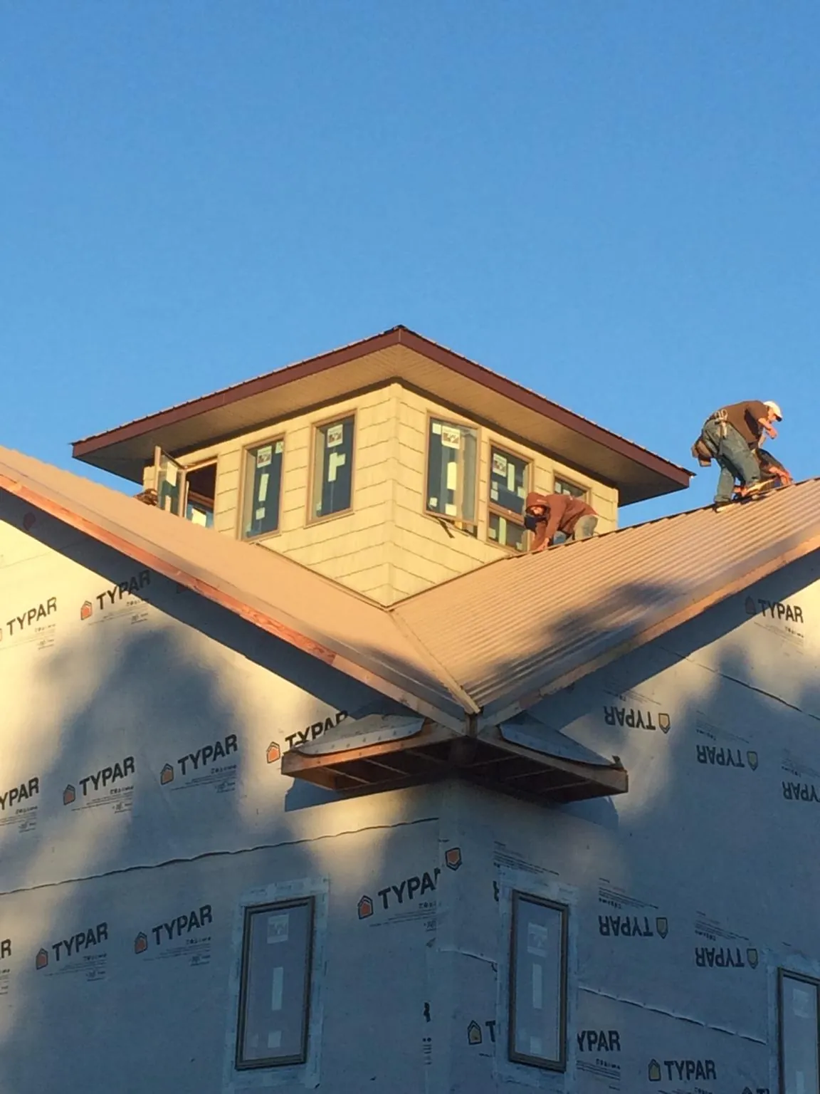 Roofers working around a rooftop cupola on a new metal roof at sunset — Roof Waterproofing in Gulf Hammock by Roofing Brothers